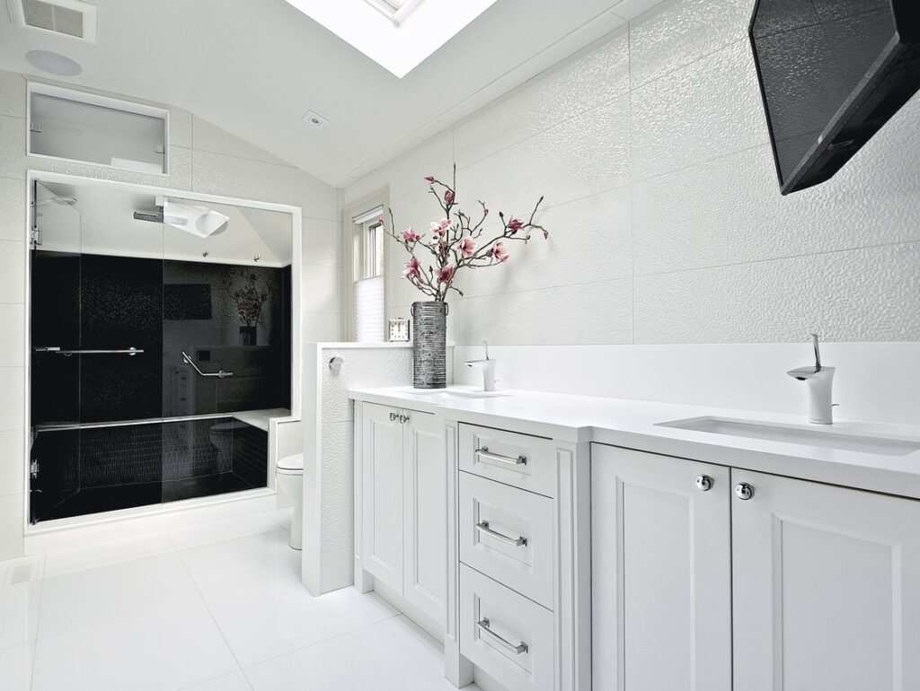A bathroom with white cabinets and light-gray walls