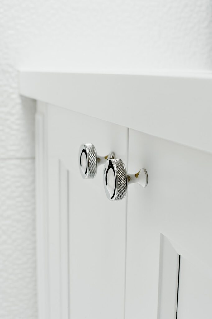 A picture of a white cabinet with silver handles